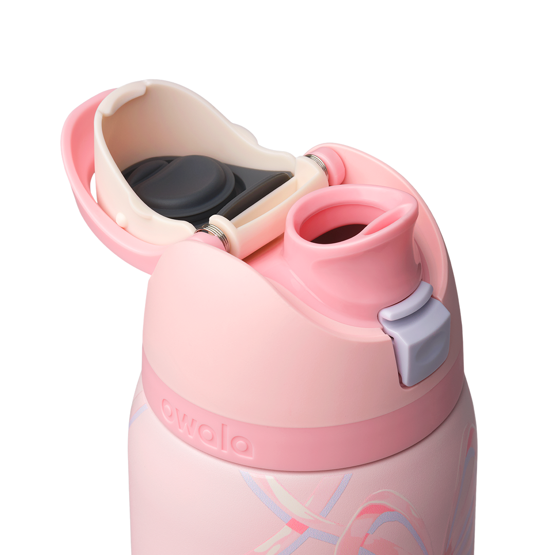 Owala FreeSip 32oz in Sugar Plum Fairy, close-up of pink lid open exposing cream FreeSip spout and lilac push-button against the bow-patterned body
