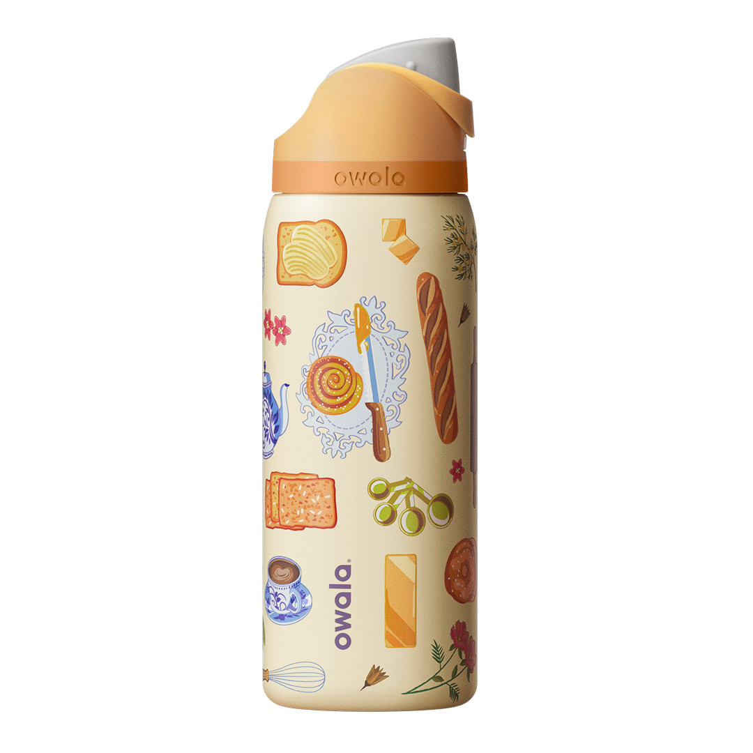 Owala FreeSip 32oz in Brunch Bunch, cream body with brunch-themed illustrations of bread, butter, pastries, teacups, and flowers, peach flip cap with cream carry loop
