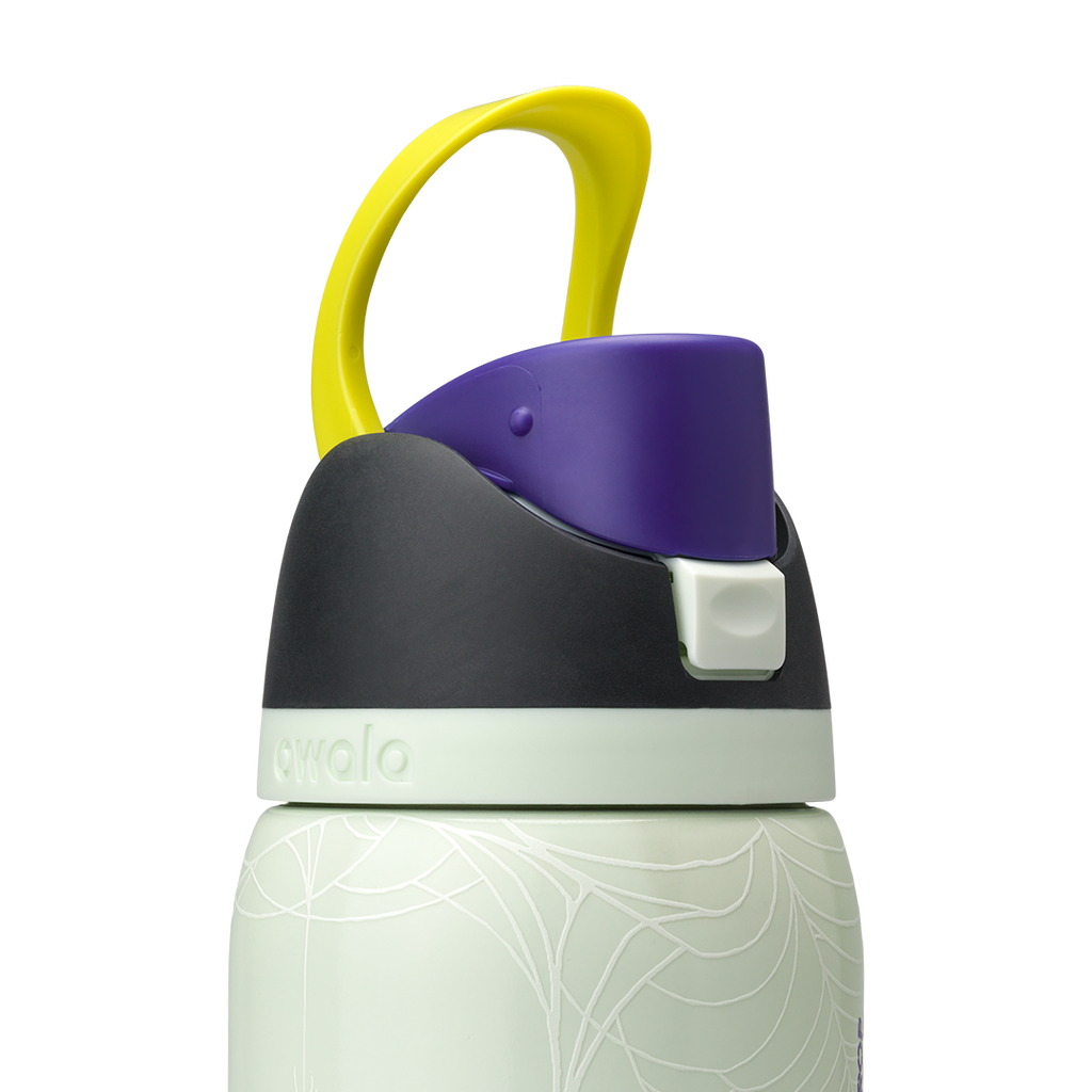 Owala FreeSip 32oz in RIP, lid detail showing dark charcoal flip cap with yellow carry loop over pale mint green body with white skeleton-hand pattern, and pale green accent ring; glows in the dark