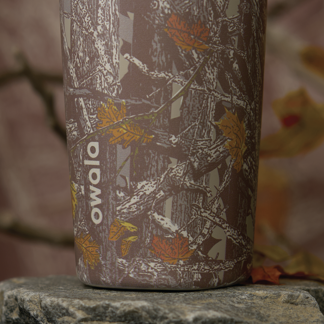 Owala SmoothSip Slider in Out of Sight, close-up of woodland camo patterned body with white Owala logo
