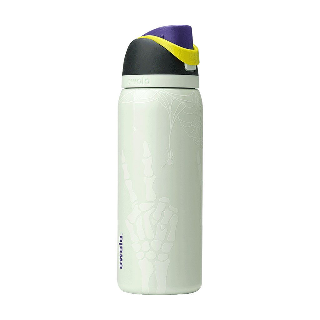 Owala FreeSip 32oz in RIP, flip cap open showing yellow-green FreeSip spout, purple lid interior with gray silicone seal, dark charcoal lid, on pale mint green body with white skeleton-hand pattern; glows in the dark